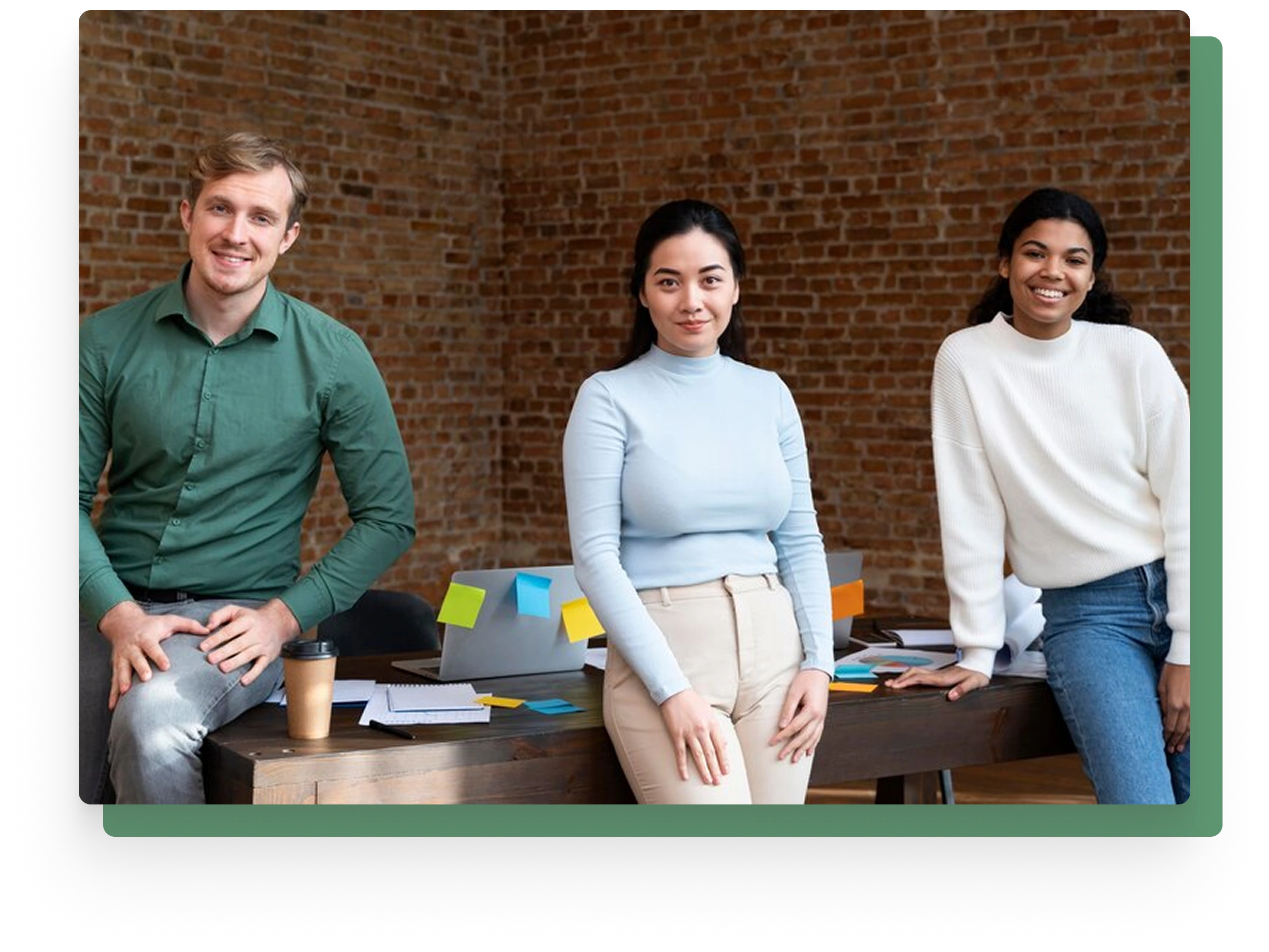 Three diverse young professionals smiling in a casual modern office setting